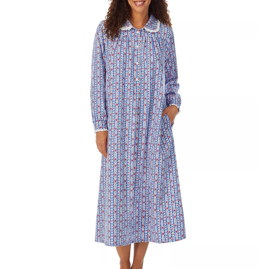 Woman in blue patterned long-sleeved nightgown with white lace collar and cuffs, standing against white background.