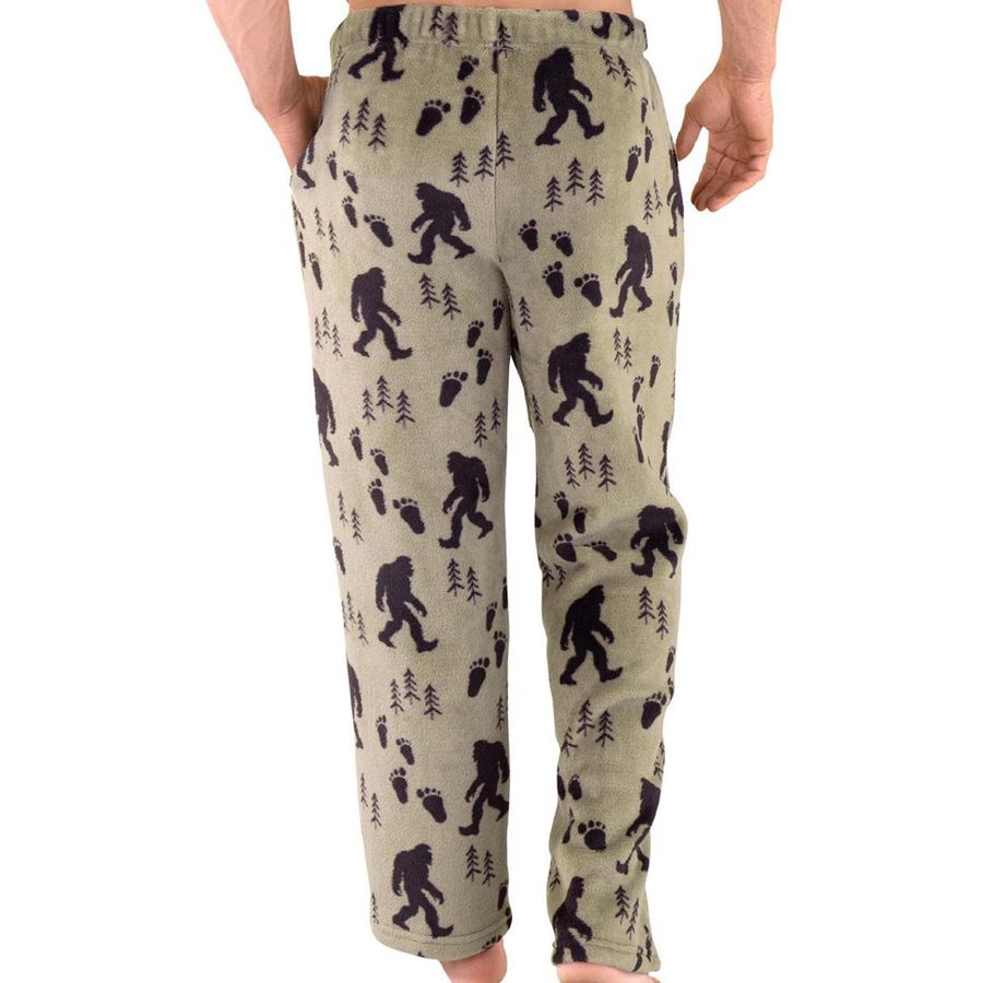 A pair of men's fleece lounge pants featuring a black Bigfoot and footprint pattern on a light khaki-beige background, modeled on a person against a white studio background.