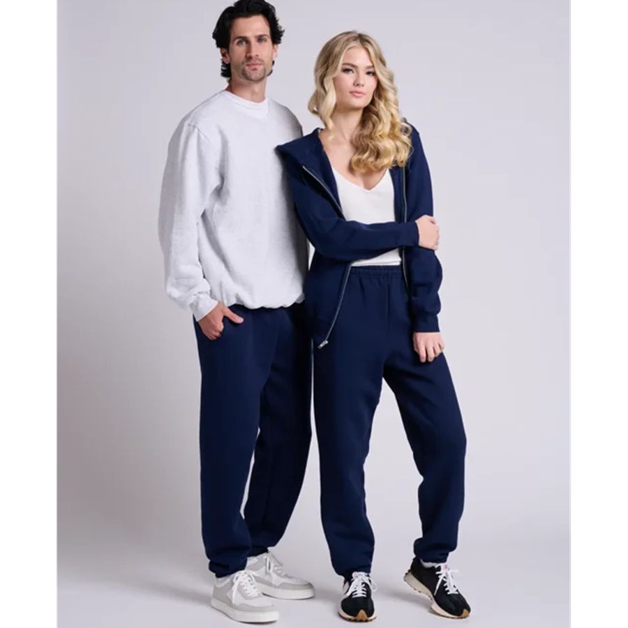 Two people wearing matching navy tracksuits on a plain background