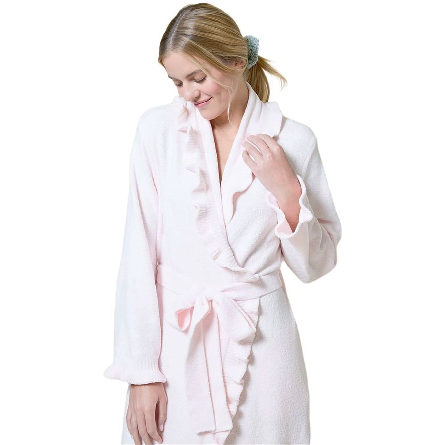 A woman wearing a light pink plush bathrobe with ruffle trim and a matching tie belt, photographed against a plain white background.