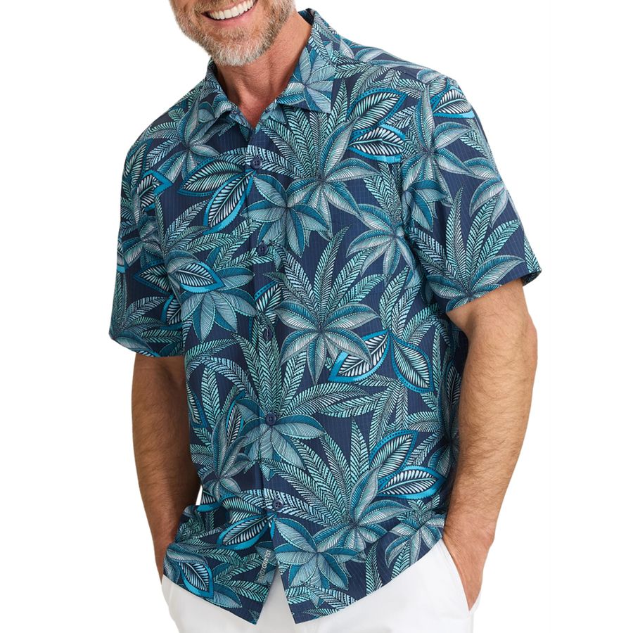 Man wearing a blue tropical patterned shirt on a white background